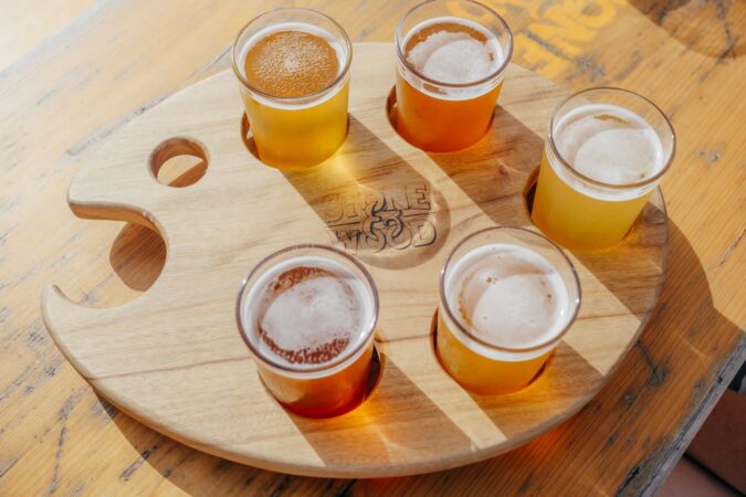 five poured drinking glasses on brown wooden tray